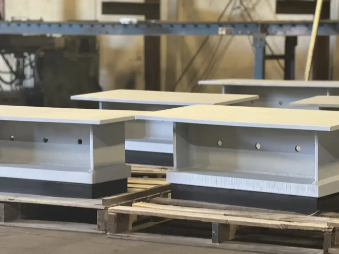 Finished laminated elastomeric bridge bearings with painted steel sole plates on a pallet